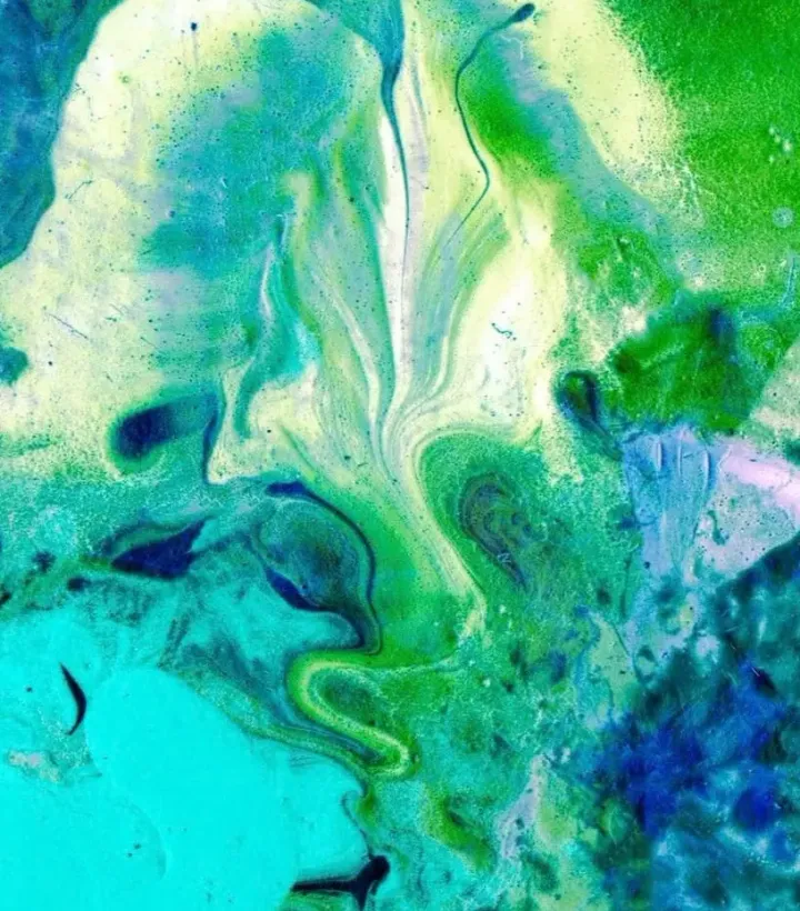 Abstract blue and green paint flowing across a textured surface